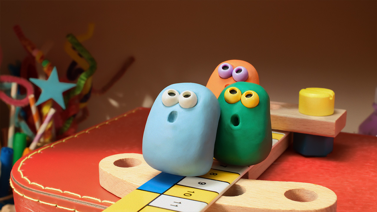 Blue, Green and Orange are staring up at the sky with their mouths open. They are sitting on a ruler 