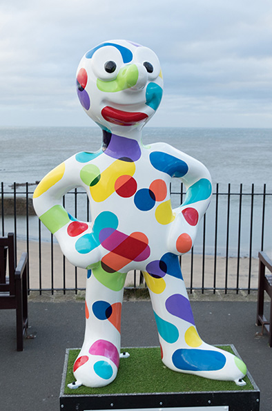 Morph statue painted white with brightly coloured dots and dashes across it 