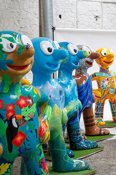 a line of 5 brightly coloured Morph statues, each decorated by artists. 